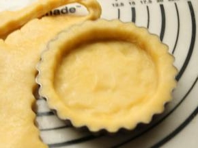 擀好的面皮揭去保鲜膜，附在模具上面，贴合模具擀去多余的部分。