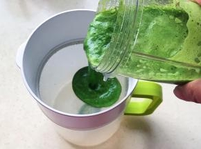 搅打好的菠菜汁倒入过滤杯子里