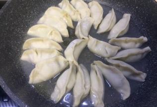 包好后全部搬放在平底锅里面，开火倒入食用油，再倒入能淹没饺子三分之一处的清水，可加盖焖