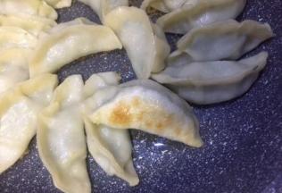 饺子在煎制过程中需要晃动锅两三次，以达到受热均匀的效果，水干后饺子皮变微透明底部已有焦黄色