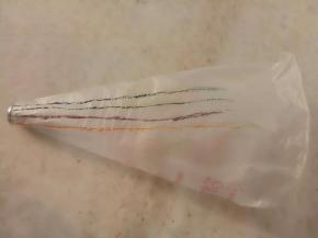 裱花袋放入裱花嘴把里面翻过来，用牙签粘色素在裱花袋上画上喜欢的颜色。淡奶油180克，糖粉18克打至8分发。