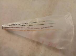 裱花袋放入裱花嘴把里面翻过来，用牙签粘色素在裱花袋上画上喜欢的颜色。淡奶油180克，糖粉18克打至8分发。