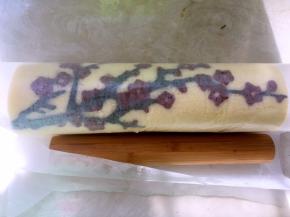 之后用擀面杖，将铺在底下的油纸卷起来，借助擀面杖的力量将蛋糕卷卷起来，入冰箱冷藏20分钟定型