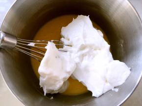 取三分之一打发好的蛋白霜，加入到蛋黄糊中，先用蛋抽翻拌均匀