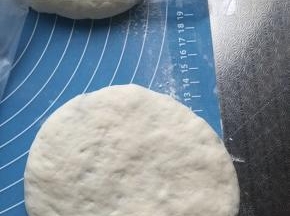 将松弛好的包子轻压，再逐个擀薄成馅饼生胚，保鲜膜覆盖，醒发15分钟。