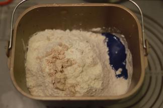 再倒入粉类，酵母放中间，启动和面功能，时间设置20分钟，成团放入盐，揉至12分钟后放入黄油