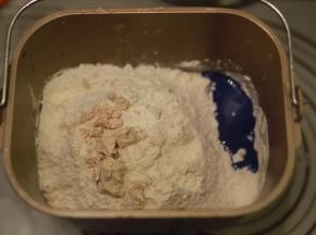 再倒入粉类，酵母放中间，启动和面功能，时间设置20分钟，成团放入盐，揉至12分钟后放入黄油