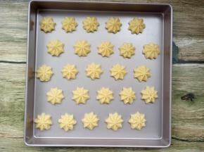 裱花袋头上剪个口，在不粘烤盘内垂直挤出曲奇，我用的是28*28的方盘；