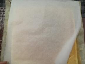 用一张干净的油纸盖在蛋糕上，翻面，揭开油布，盖在蛋糕上，再翻过来，用油纸盖上。