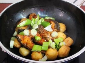 将炸锅的鱼块、大葱、青辣椒一起下锅；