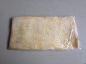 将黄油面团用保鲜膜包裹，用擀面棍压成长方形的0.5CM左右厚的薄面片，放进冰箱冷冻层冷冻至硬