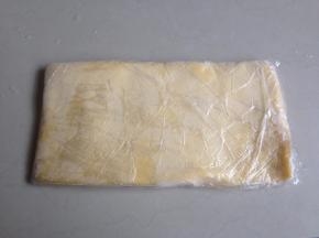 将黄油面团用保鲜膜包裹，用擀面棍压成长方形的0.5CM左右厚的薄面片，放进冰箱冷冻层冷冻至硬