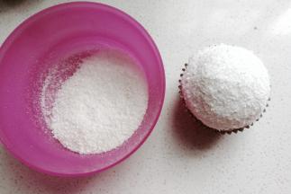 再倒入适量椰蓉在小碗中，左手拿碗右手拿纸杯蛋糕，让奶油部分在椰蓉中滚一圈沾满椰蓉