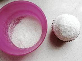再倒入适量椰蓉在小碗中，左手拿碗右手拿纸杯蛋糕，让奶油部分在椰蓉中滚一圈沾满椰蓉