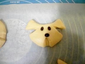 剪完以后用手再按压一下接缝，让它能粘合的更紧密一些，防止发酵的时候面团长大，会张开。（我也听幸福de眼泪好好按压了，可是还是没有做好，导致烤出来的小狗面包好丑，耳朵也都张开了，所以一定要把幸福de眼泪和我操作上的经验传授给大家，让大家能做出漂亮的小狗面包）用黑豆装上狗的眼睛和鼻子，眼睛竖着放，鼻子横着放。