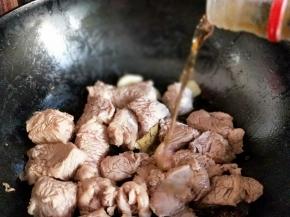 待牛肉炒至变色后加入料酒。