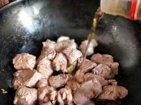待牛肉炒至变色后加入料酒。
