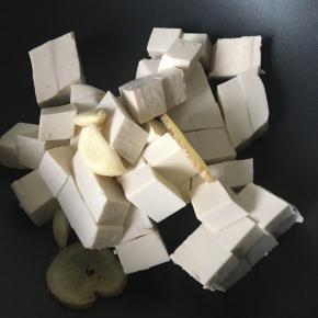 锅中放豆腐、姜片和大蒜头