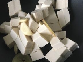 锅中放豆腐、姜片和大蒜头