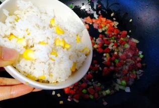 加入提前放蒸笼煲蒸好的玉米粒饭，翻炒均匀