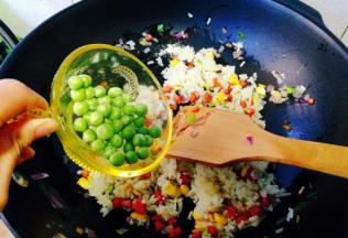 陆续加入豌豆粒，再次翻炒均匀，