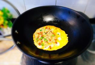 将蛋皮再次回锅里回温下，将炒饭摆到一半蛋皮上。