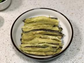 取出蒸熟的茄子，放温热不烫手后先把每一半茄子对半切开，然后用手撕成小长条，摆放在盘子内
