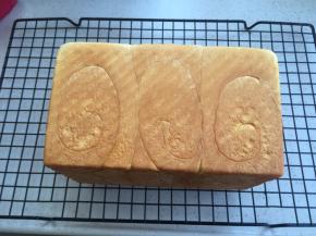 出炉侧倒，边震吐司盒边倒出吐司在网架上。