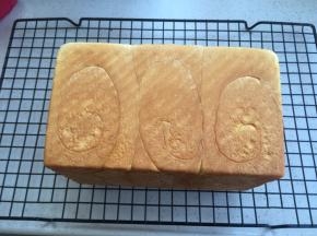 出炉侧倒，边震吐司盒边倒出吐司在网架上。