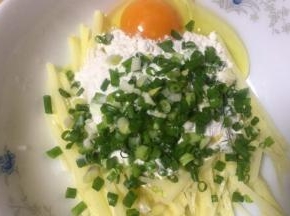 土豆去皮切细（手工切滴，刀工还算过得去吧）放入切了的葱花，土豆丝装入碗里打入鸡蛋放面粉