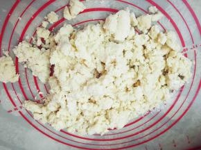 将和面桶里的雪花状面团倒在硅胶垫上。