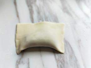 将馄饨皮对折，将周边一圈压紧，如图。