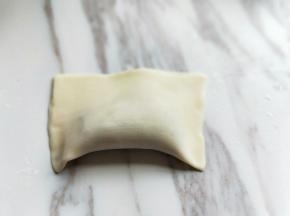 将馄饨皮对折，将周边一圈压紧，如图。