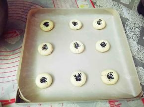 食指沾水，醮上黑芝麻，在饼胚中间戳一个洞，动作要轻。