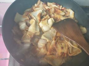 倒入五花肉和千页豆腐，放酱油，盐，翻炒。