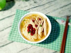 把煮好的面条放到碗里，摆上鸡肉丝和花生。