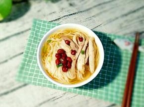 把煮好的面条放到碗里，摆上鸡肉丝和花生。