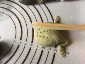 将面条如图折成青蛙腿，用锋利的刻出青蛙爪子，再用干净梳子在青蛙背上轻按压出3条细纹