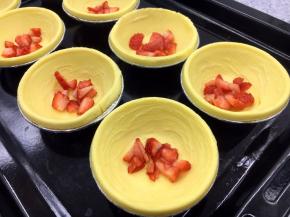 在蛋挞皮里放入少许的草莓碎。