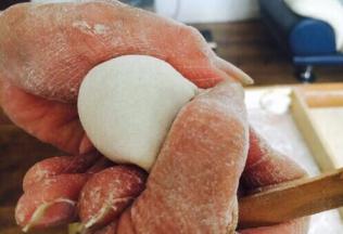 往饺子皮上放适量的饺子馅。先将饺子皮对折，中间捏紧，然后用双手的拇指和食指将饺子皮的边向中间轻轻挤压。