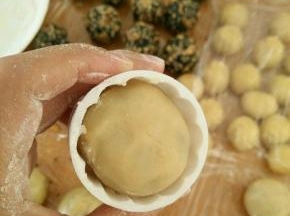 模具放适量熟粉进去转一圈再倒出来，月饼坯也抹点熟粉，然后放到模具里。烤箱预热190度。