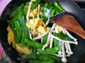 倒入荷兰豆和白玉菇，放盐，翻炒。