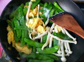 倒入荷兰豆和白玉菇，放盐，翻炒。