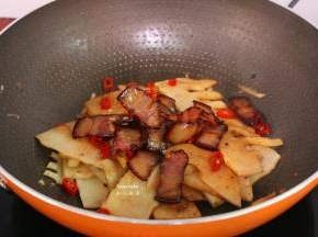 放入切好的辣椒、煎好的腊肉