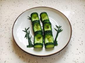 将挖好槽的6节黄瓜节摆放在盘子里，用黄瓜皮剪成小竹叶，装饰一下。