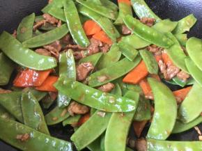 放入胡萝卜片和荷兰豆，翻炒至熟透。