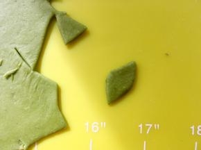 菠菜面团用擀面杖擀扁，用剪刀剪出叶子的形状