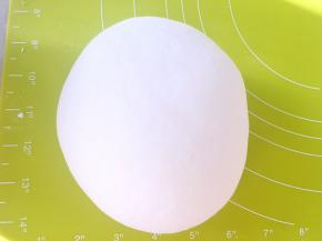 和好的面团倒在揉面垫上，一直揉至面团表面光滑