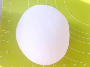 和好的面团倒在揉面垫上，一直揉至面团表面光滑