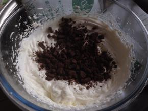 烘烤结束将蛋糕取出，晾2-3分钟，再倒扣在另一张干净的油纸上，撕掉底部油纸，卷一下定型，再摊开。淡奶油加糖隔冰水打发，倒入奥利奥饼干碎，拌均匀